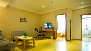 Ein Wohnzimmer mit einer Couch, einem Couchtisch, einem Fernseher und einer Pflanze.