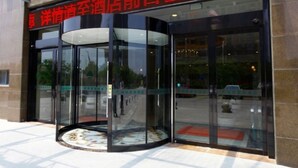 A hotel entrance with a glass revolving door and a sign in Chinese. - GreenTree Inn Yancheng Dongtai Huiyang Road Guofu Hotel (Yancheng)