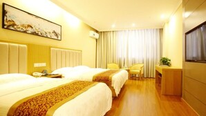A hotel room with two beds, a desk, a chair, and a large window with curtains. - GreenTree Inn Yancheng Dongtai Huiyang Road Guofu Hotel (Yancheng)