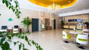 A modern hotel lobby with a chandelier, reception desk, seating area, and a green plant. - GreenTree Inn Yancheng Dongtai Huiyang Road Guofu Hotel (Yancheng)