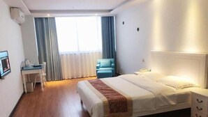 Een hotelkamer met een bed, nachtkastje, stoel en een bureau met een stoel.