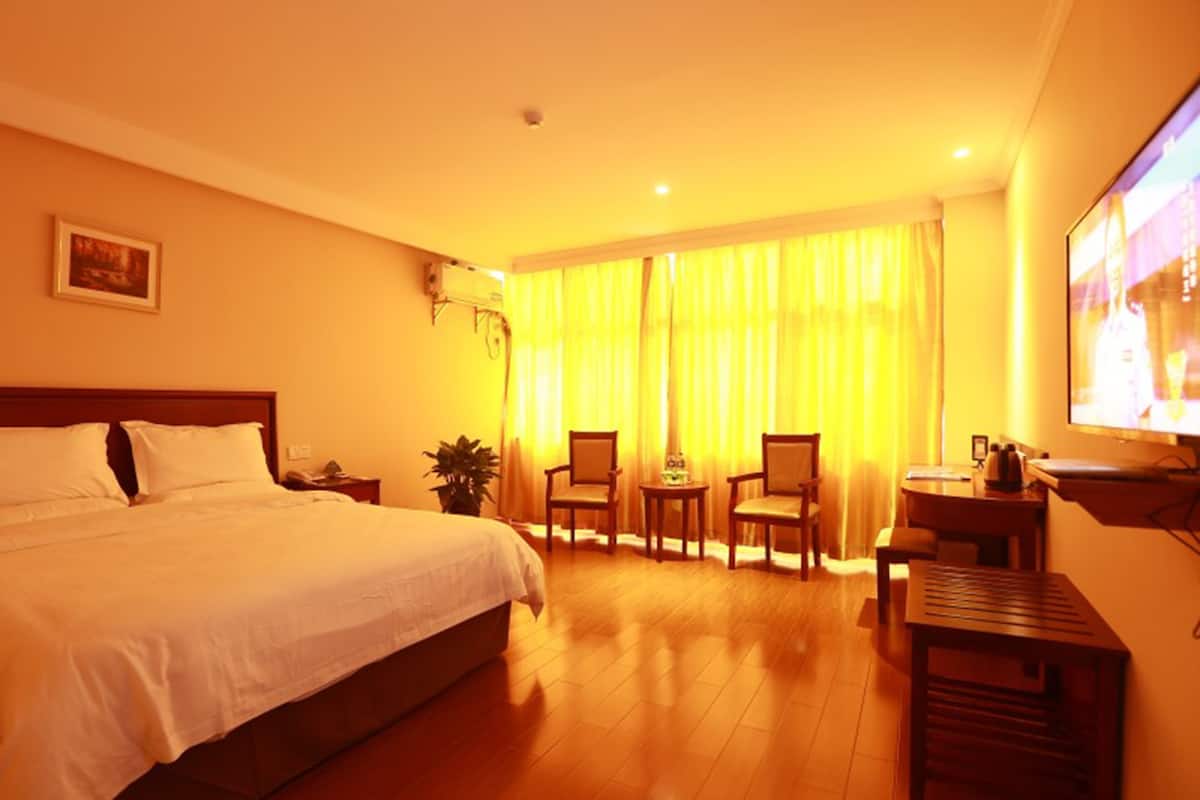 Une chambre d’hôtel avec un grand lit, un bureau avec une chaise, une petite table et un téléviseur.