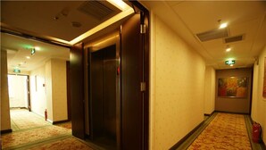 A hotel corridor with carpeted floors, wooden doors, and a fire extinguisher. - GreenTree Inn Yangquan District Desheng Street Industry and Trade Building Express Hotel (Yangquan)