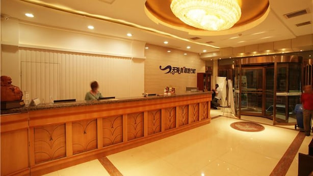 A hotel reception area with a wooden reception desk, a large chandelier, and a revolving door. - GreenTree Inn Yangquan District Desheng Street Industry and Trade Building Express Hotel (Yangquan)