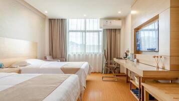 A hotel room with two beds, a desk, a chair, a television, and a window with curtains.
