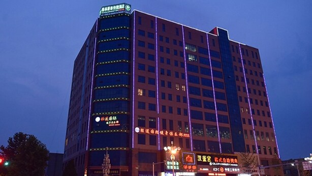 A multi-story hotel with illuminated signage and a prominent entrance. - GreenTree Inn BaoDing Xiong county XiongZhou Road Express Hotel (Baoding)