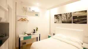 A hotel room with a bed, a desk with a plant, a mirror, and artwork on the wall. - GreenTree Inn TaiZhou XianJu Passenger Center West HuanCheng Road Express Hotel (Taizhou)