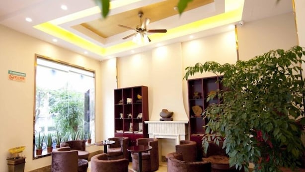 A modern interior with a ceiling fan, a large window, and a variety of seating arrangements including round tables and cushioned chairs. - GreenTree Inn TaiZhou XianJu Passenger Center West HuanCheng Road Express Hotel (Taizhou)