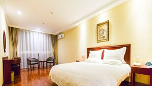 A hotel room with a large bed, a desk, a chair, and a window with curtains.