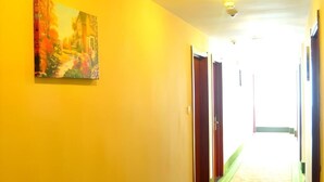 Un pasillo con una pared amarilla, un cuadro y una puerta.
