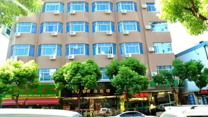 Un edificio de varios pisos con fachada uniforme, unidades de aire acondicionado y varios escaparates en la planta baja.