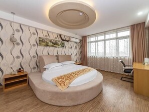 A modern hotel room with a curved bed, a desk, and a large window with curtains. - Greentree Inn Shanghai Minhang District Hongqiao Hub Qibao Express Hotel (Shanghai)