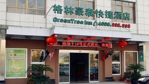 A hotel entrance with signage in a foreign language, a green awning, and potted plants.
