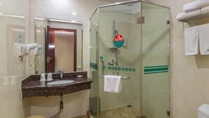 A hotel bathroom with a glass-enclosed shower, a sink with a marble countertop, and a toilet.