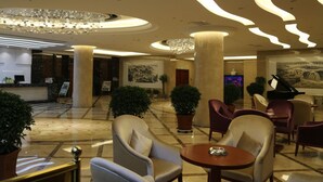 En lobby med reception, siddeområde og en stor lysekrone.