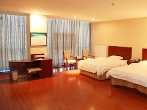 Una habitación de hotel con dos camas, un escritorio, una silla y un radiador.