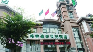 A hotel with a modern architectural design, featuring a prominent curved glass facade and multiple flags displayed above the entrance.