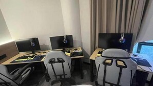 A hotel room with two desks, each with a computer and a chair.