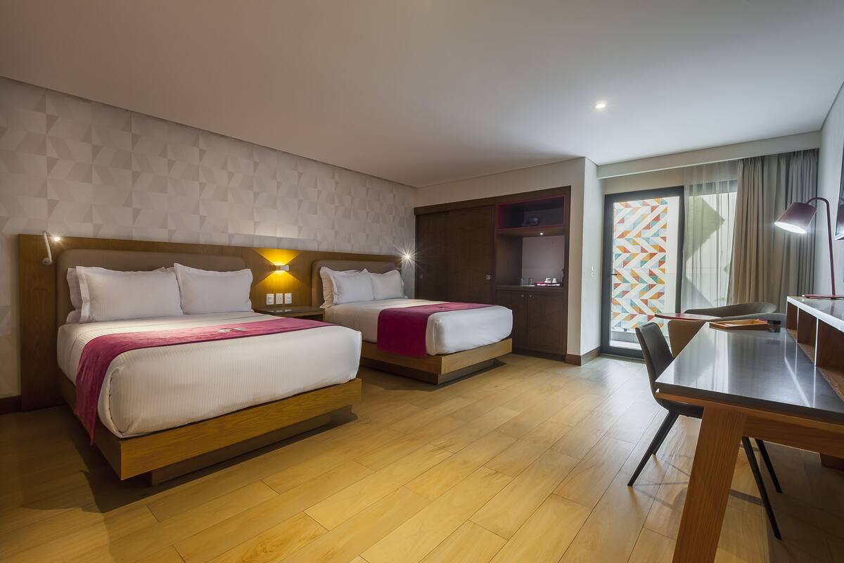 Een hotelkamer met twee bedden, een bureau en een stoel.