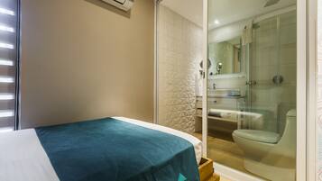 A bedroom with a bed, a bathroom with a shower, and a toilet.