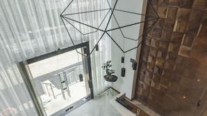 Un intérieur moderne agrémenté d’un luminaire aux formes géométriques, d’une cloison en verre et d’un mur en bois.