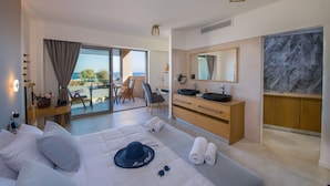 Una habitación de hotel moderna con cama, escritorio, baño con salpicadero de mármol y balcón con vistas.