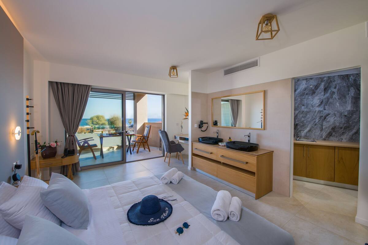 Une chambre d’hôtel moderne dotée d’un lit, d’un bureau, d’une salle de bain avec un revêtement mural en marbre et d’un balcon offrant une vue.