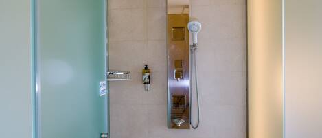 Baño con botón para agua caliente y fría, dispensador de jabón y cabezal de ducha.