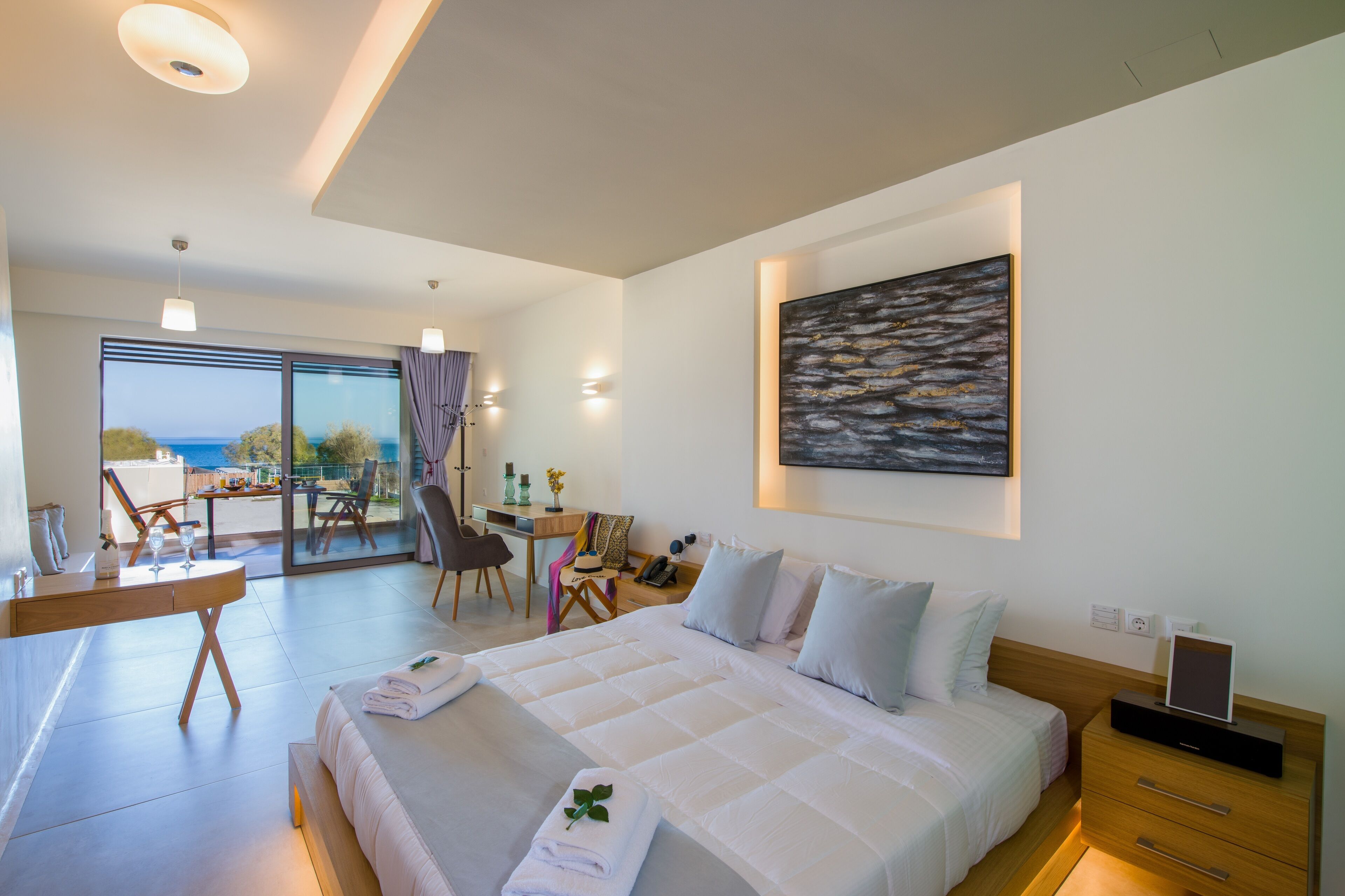 Una habitación de hotel moderna con una cama grande, un escritorio y un balcón con vistas.