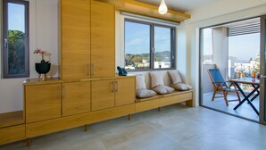 Una sala de estar moderna con un mueble de madera, un banco con cojines y vistas al exterior a través de ventanas amplias.