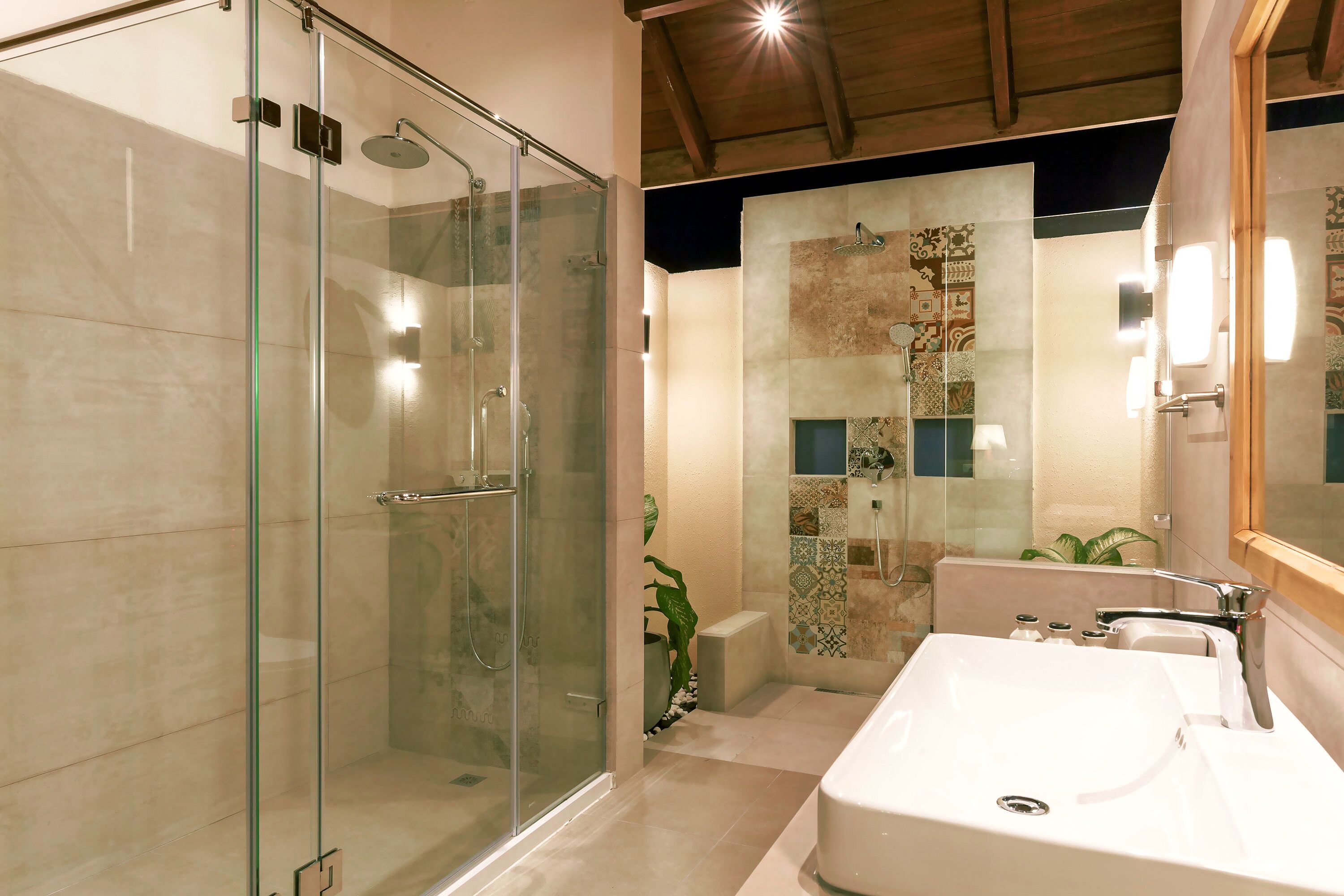 Un baño moderno con ducha de vidrio, un lavamanos grande de color blanco y azulejos decorativos.