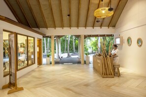 A spacious lobby with a wooden floor, a reception desk, and a view of the outdoors.