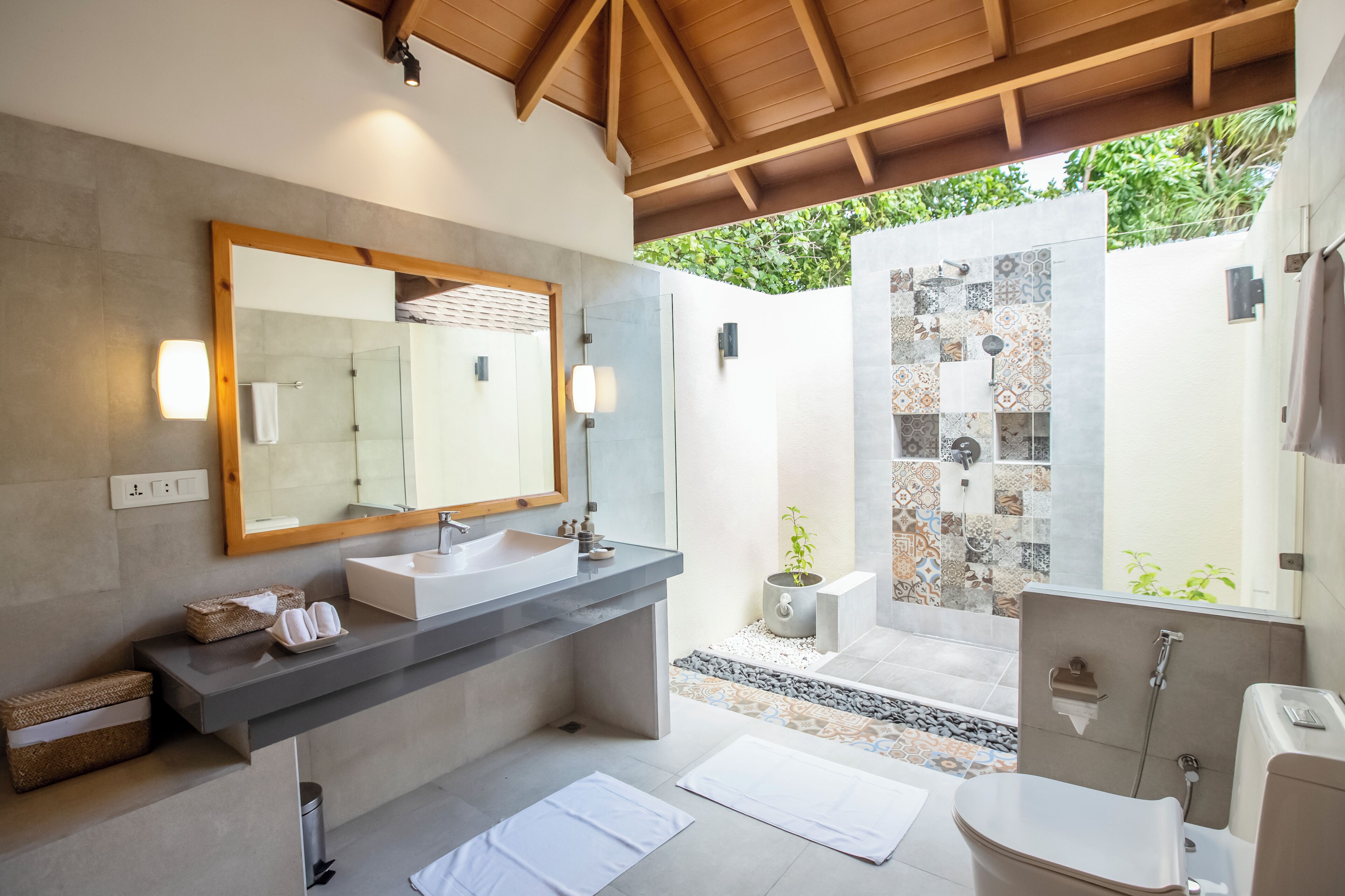 Een moderne badkamer met een grote spiegel, twee wastafels, een douche en een toilet.