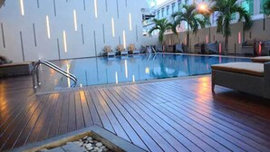 A pool area with wooden decking, lounge chairs, and a modern wall design. - Nagoya Hill Hotel Batam (Batam)