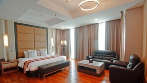 A spacious hotel room with a large bed, a leather sofa, a coffee table, and a view of the city. - Nagoya Hill Hotel Batam (Batam)