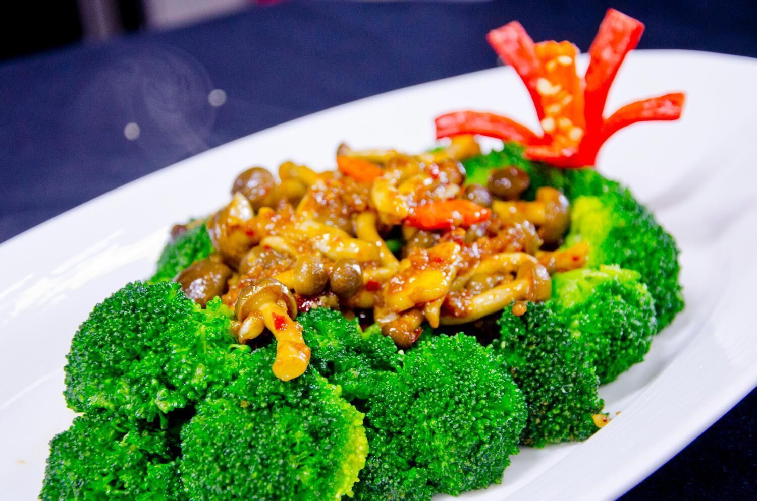A plate of stir-fried vegetables and broccoli on a white plate.