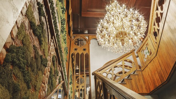 A grand staircase with ornate woodwork and a chandelier. - Familion Aparthotel (Chisinau)