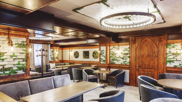 Ein Restaurant mit Holztischen und -sitzecken, Ziegelwänden und einer Kronleuchter.
