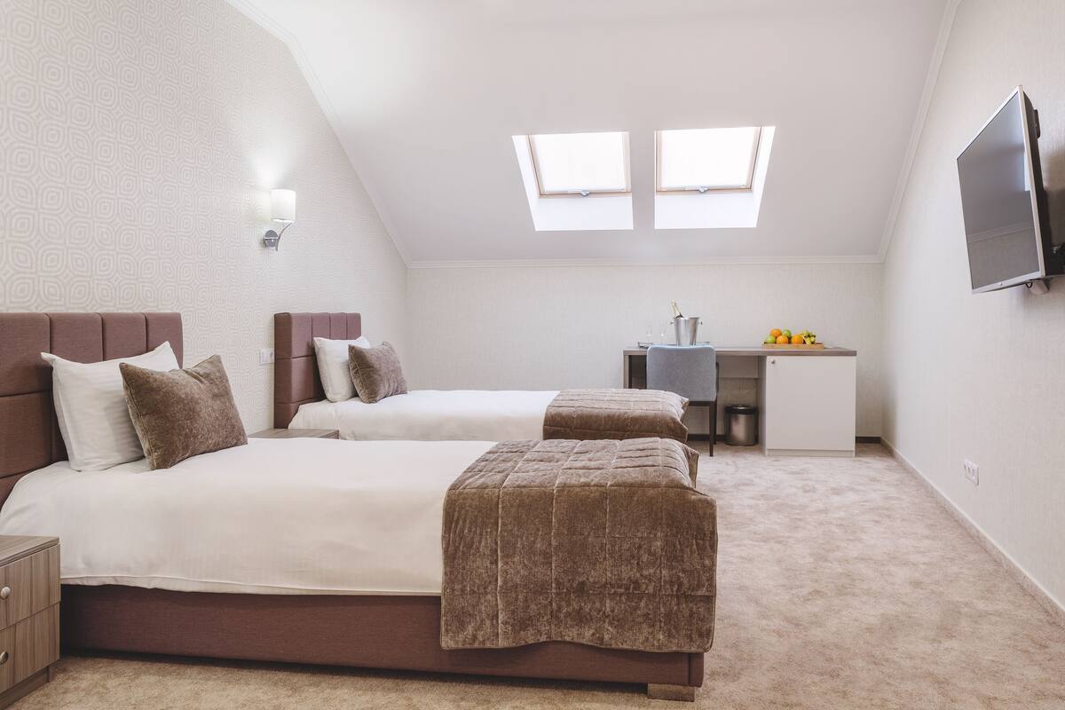 A bedroom with two beds, a desk, and a TV.