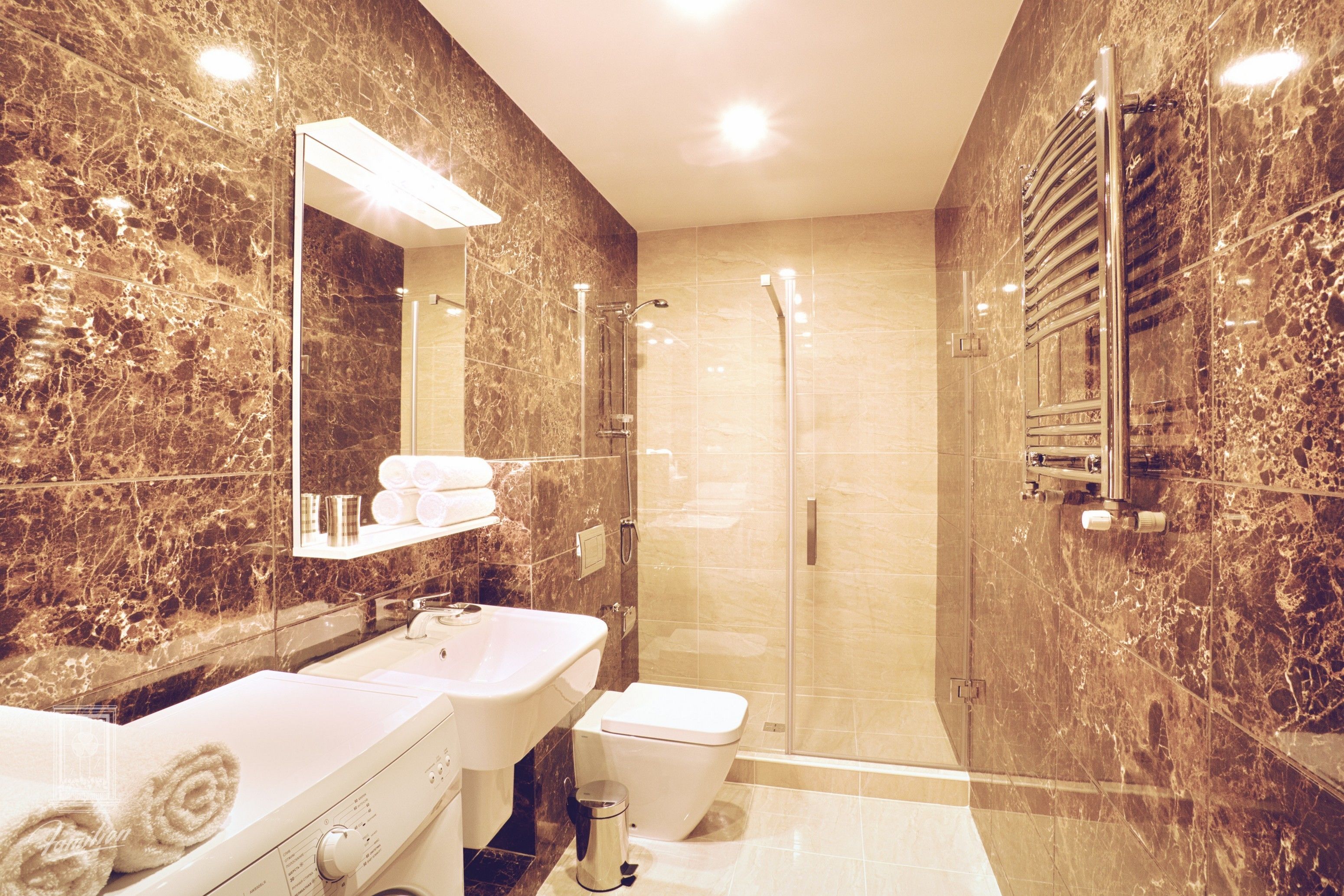 Un baño moderno con cabina de ducha de vidrio, un lavamanos blanco y un inodoro.