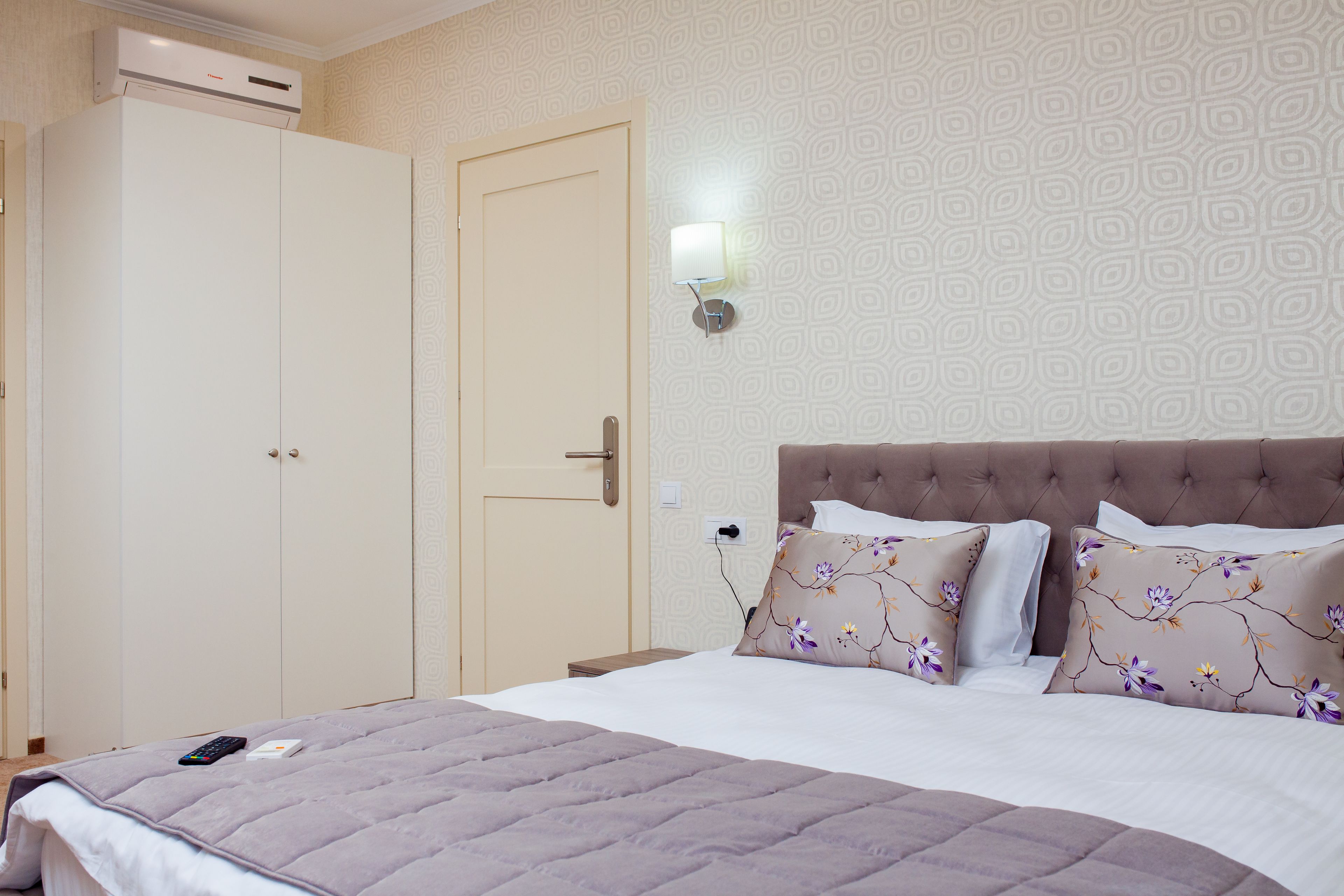 A bedroom with a bed, a wardrobe, and a wall-mounted light fixture.