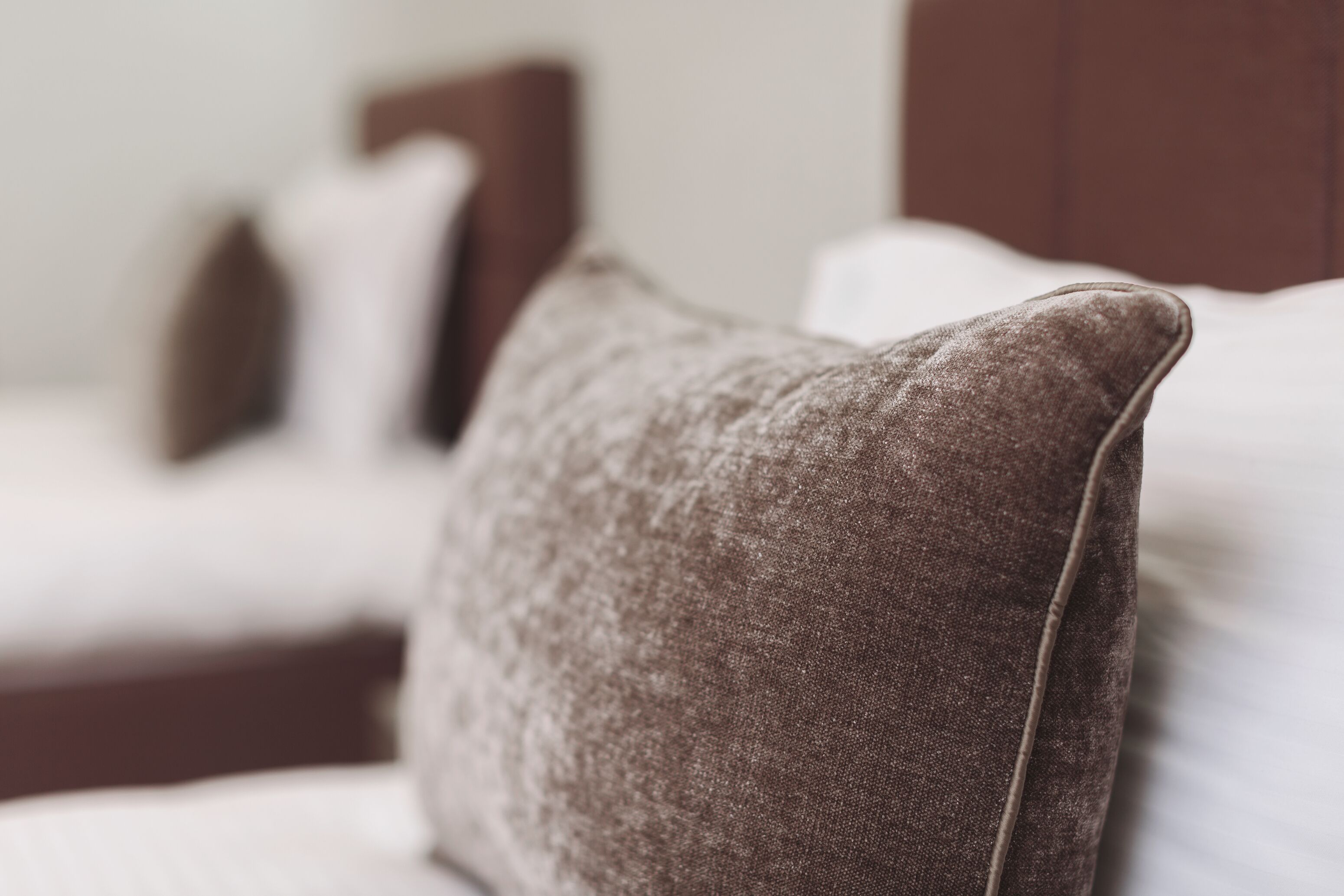 A close-up of a brown pillow on a bed with white bedding.