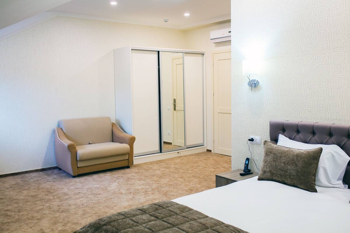 A bedroom with a bed, a nightstand, a chair, and a wardrobe.