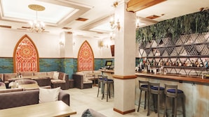 A bar area with stools, a counter, and a wall with hanging plants. - Familion Aparthotel (Chisinau)