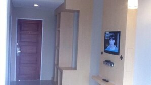 A hallway with a wooden door, a recessed shelf, and a mounted television. - Bangka City Hotel (Pangkalpinang)