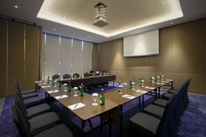 A conference room with a long table, chairs, and a projector screen. - Grandhika Setiabudi Medan (Medan)