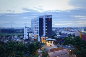A modern hotel with a prominent tower, a covered outdoor area, and a view of the surrounding cityscape. - Grandhika Setiabudi Medan (Medan)