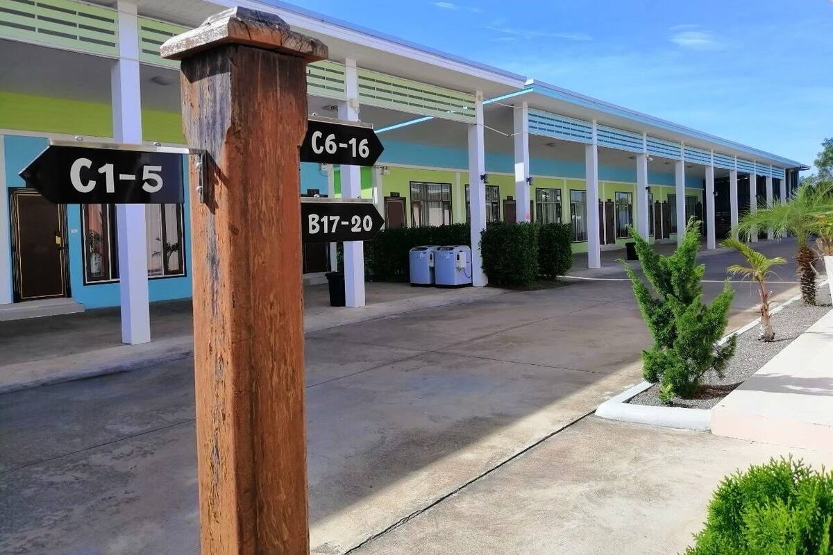 A building with a covered outdoor area, signs indicating room numbers, and a clear sky.