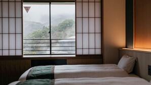 A traditional Japanese room with tatami flooring, a futon bed, and a shoji screen window overlooking a mountainous landscape. - Ureshino Motoyu (Ureshino)
