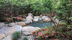 A garden with a pond, rocks, and pink flowering plants. - Ureshino Motoyu (Ureshino)